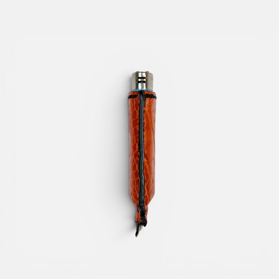 Détail des écailles du cuir d'alligator orange sur l'étui à briquet MRLM